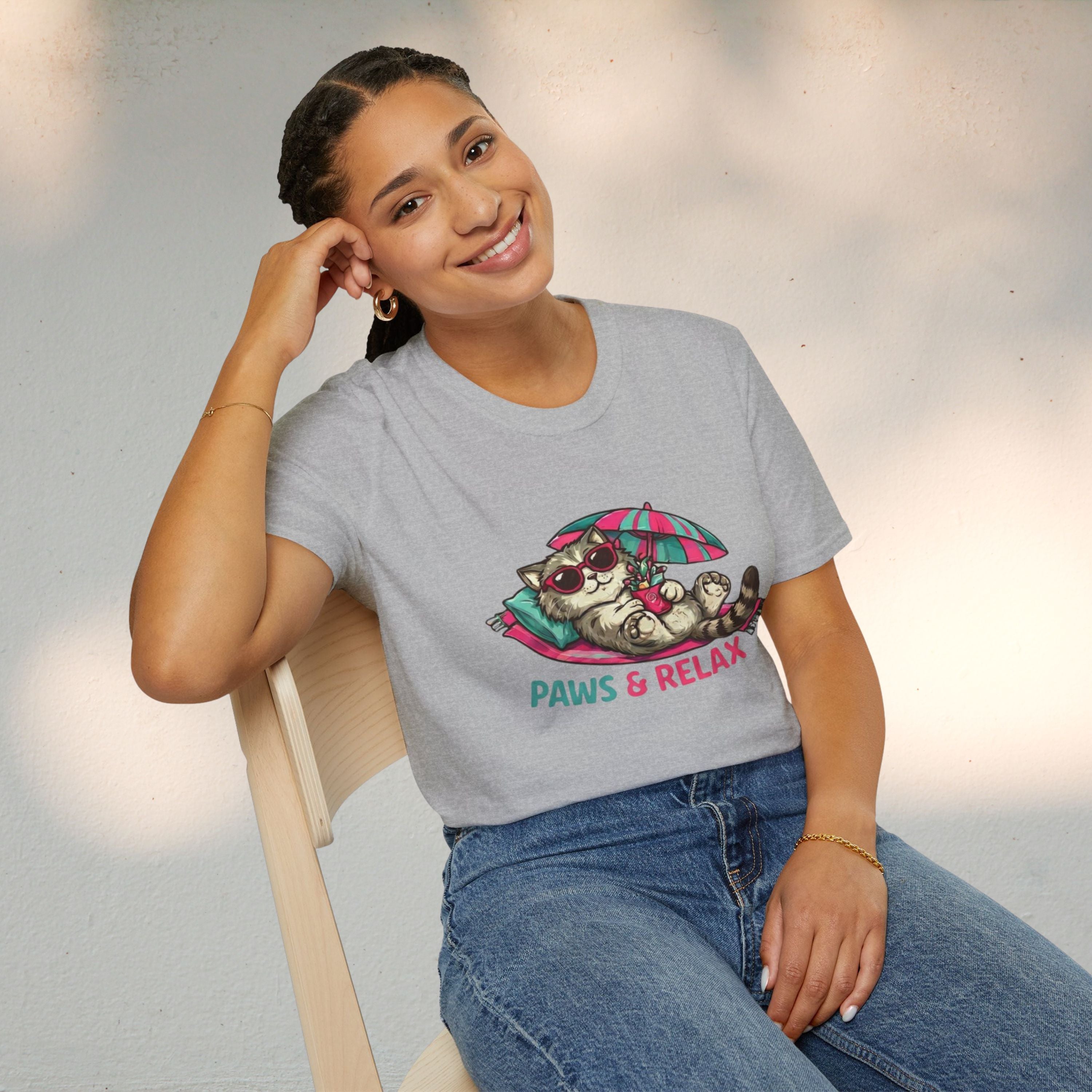 Person wearing a gray t-shirt with a cat graphic and 'Paws & Relax' text, sitting on a chair.